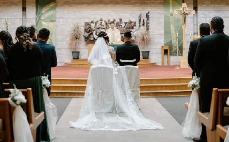 The backs of a couple getting married standing at the altar