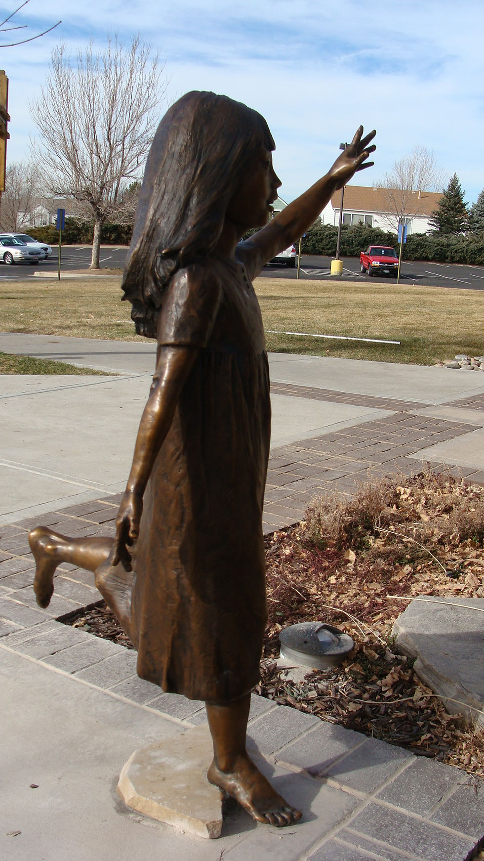 A bronze statue of a girl reaching outwards