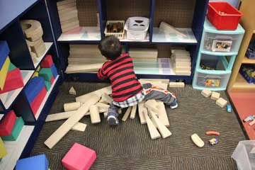 A boy in a blue and red striped shirt playing in a classroom