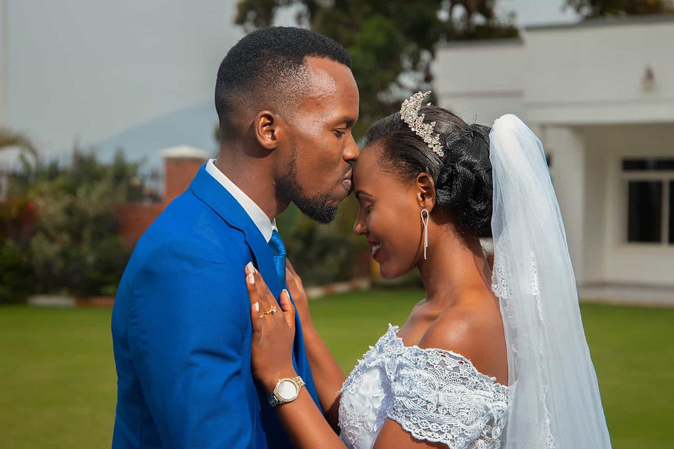 A groom kissing his bride on the head in their wedding attire