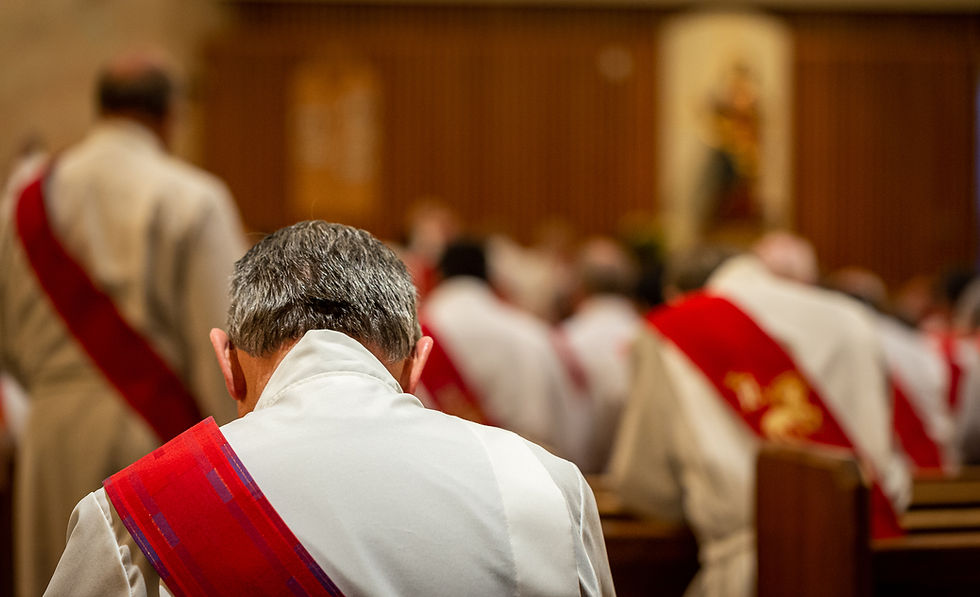 A deacon with a red stole kneeling in a church praying